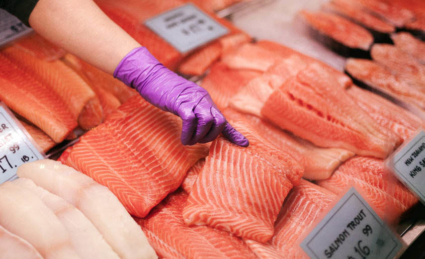 Rainbow trout meat in a fish store and a woman pointing to fish